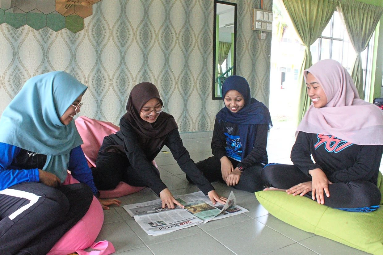 Expensive activity: Nur Alia (second from left) says reading L'Ã‰toile with her friends is a precious part of her high school years.