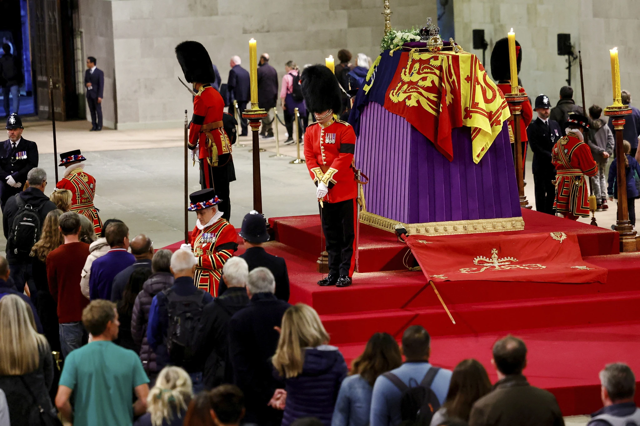 Members of the public walk past the Queen's coffin with soldiers in full dress and bearskin hats standing guard